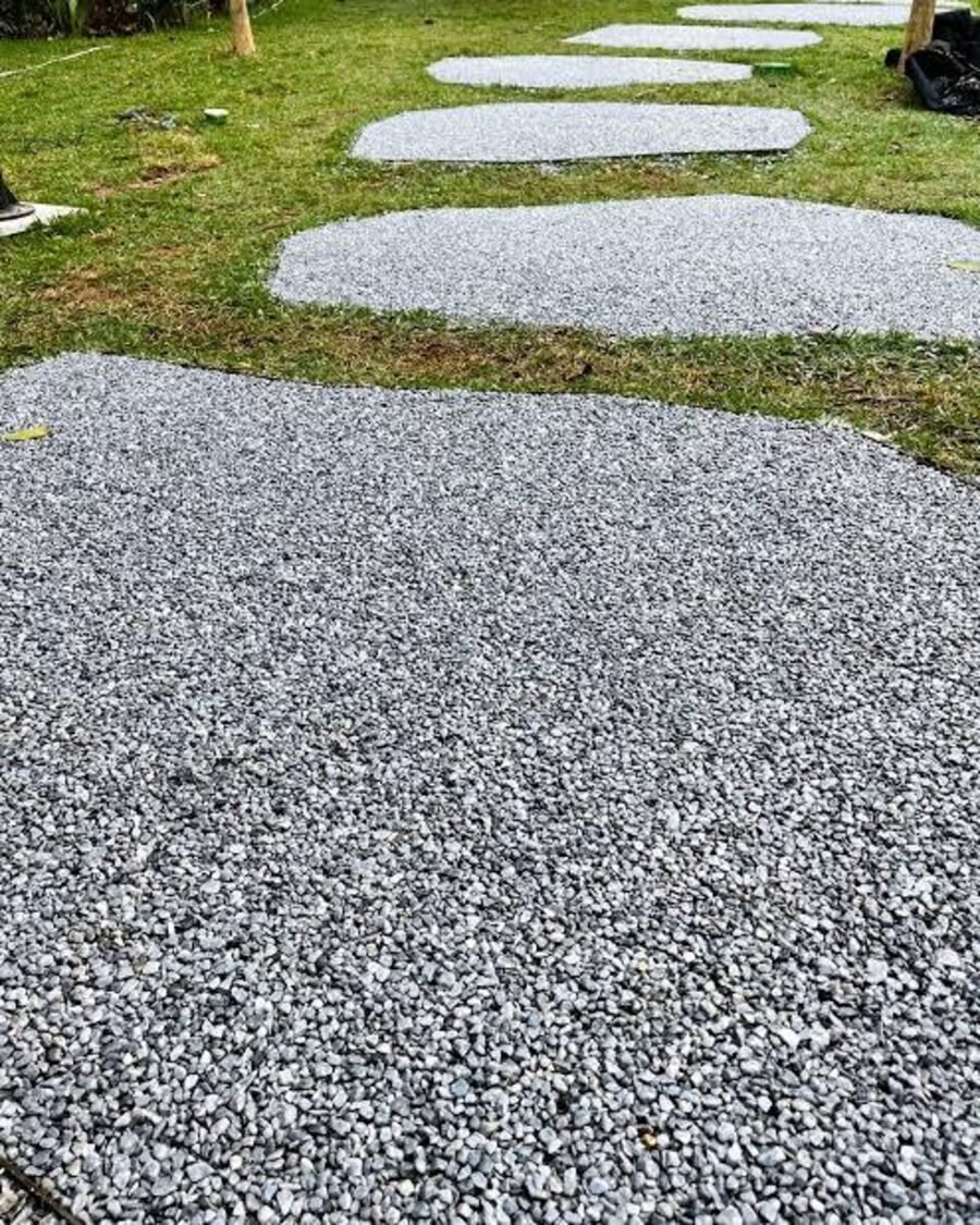 Caminho externo com piso drenante e pedras de passagem