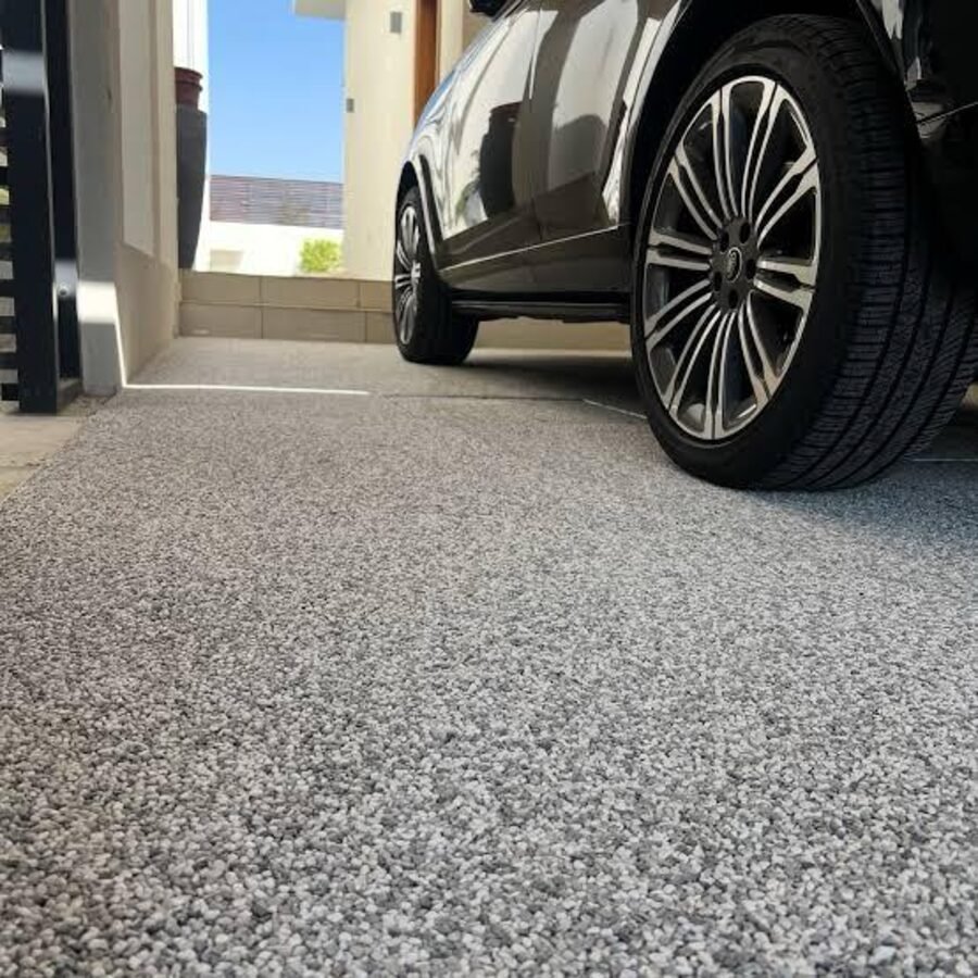 Garagem com piso natural em tom grafite e carro estacionado